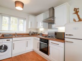 A kitchen with white cabinets and appliances at Poldam in St Austell