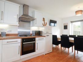 A kitchen with a gas stove and dining area at Poldam in St Austell