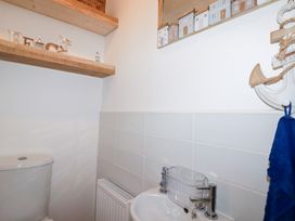 A bathroom with toilet, sink and shelf at Poldam St Austell
