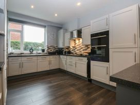 A kitchen with cabinets, sink, and appliances at Ty Llwyd in Llandudno