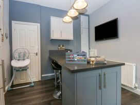 A kitchen with a kitchen island and high chair at Ty Llwyd in Llandudno