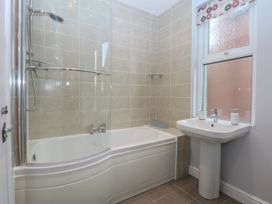 A bathroom with a shower over a bathtub and a basin at Ty Llwyd in Llandudno