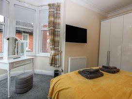 A bedroom with a bed, dressing table, and television at Ty Llwyd in Llandudno