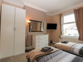 A bedroom with a wardrobe, mirror, and twin beds at Ty Llwyd in Llandudno