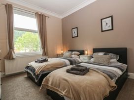 A bedroom with two single beds and a window at Ty Llwyd in Llandudno