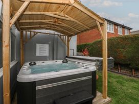 A hot tub under a wooden gazebo in a garden at Ty Llwyd in Llandudno