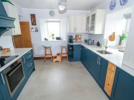 A kitchen with blue cabinets and stools at Claddagh Tuss Holiday Cottage in Clifton