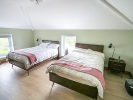 A bedroom with two beds and windows at Claddagh Tuss Holiday Cottage in Clifton