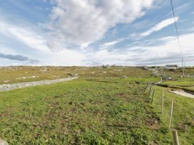 A grassy area with fences and distant houses at Claddagh Tuss Holiday Cottage in Clifton