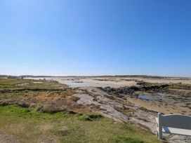 A coastal landscape featuring sand, rocks, and a bench at Claddagh Tuss Holiday Cottage, Clifton