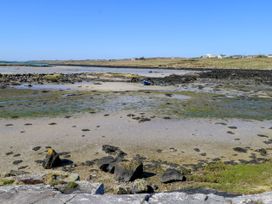 A shore with rocks and a boat at Claddagh Tuss Holiday Cottage in Clifton