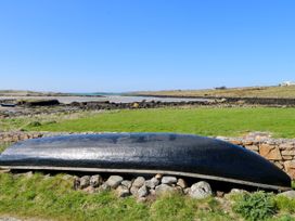 A boat on grass near water at Claddagh Tuss Holiday Cottage in Clifton