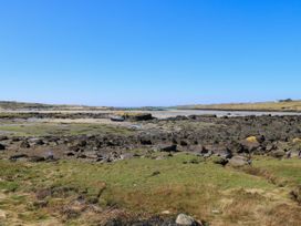 A coastal area with rocks and a boat at Claddagh Tuss Holiday Cottage in Clifton