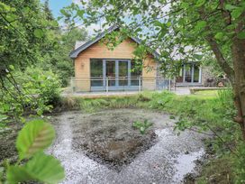 A house by a pond surrounded by trees at Bracken Ground Coniston