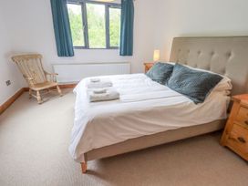 A bedroom with a bed, bedside table, and rocking chair at Bracken Ground in Coniston