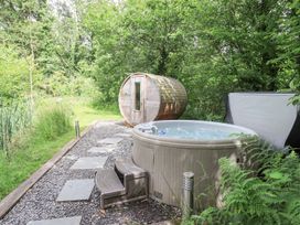 A hot tub and sauna in a garden area at Bracken Ground in Coniston