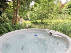 A hot tub in a garden with trees and grass at Bracken Ground in Coniston