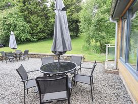 An outdoor garden with a table, chairs and a parasol at Bracken Ground in Coniston