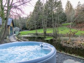 A hot tub beside a pathway and water body at Bracken Ground in Coniston