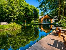 A house by a pond with trees and a deck at Bracken Ground in Coniston