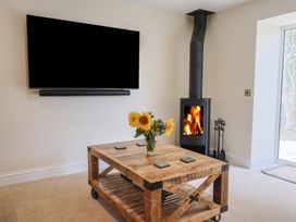 A living room with a television and wood stove at Foxes Den Pendomer near Yeovil, Somerset