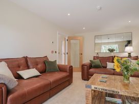 A living room with brown sofas and a wooden table at Foxes Den, Pendomer near Yeovil, Somerset