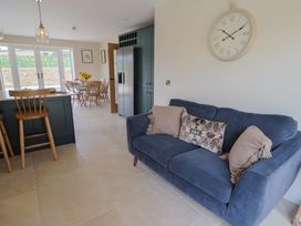 A kitchen with a sofa, dining table, and refrigerator at Foxes Den Pendomer near Yeovil, Somerset