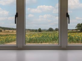 A view of a sunflower field through a window at Foxes Den Pendomer near Yeovil, Somerset