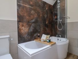 A bathroom with a bathtub, shower, and items on a tray at Foxes Den, Pendomer near Yeovil, Somerset