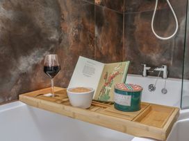 A bathtub tray with a wine glass, a book, a candle, and a bowl at Foxes Den in Pendomer near Yeovil, Somerset