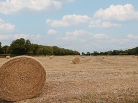 A field with hay bales under a cloudy sky at Foxes Den Pendomer near Yeovil, Somerset
