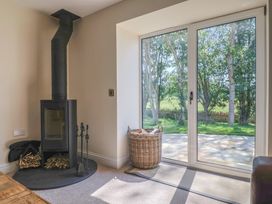 A snug with a wood stove and a basket at The Fox Den in East Coker