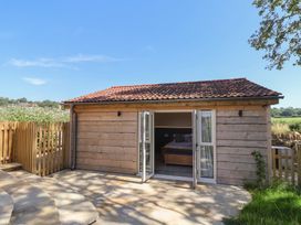 A wooden cabin with sliding doors and an outdoor patio at The Fox Den in East Coker