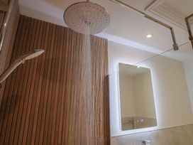 A bathroom with a shower head, handheld shower, and mirror at The Fox Den in East Coker