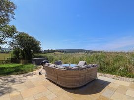 An outdoor seating area with a table and view of fields at The Fox Den in East Coker