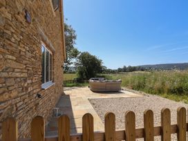 An outdoor area with a stone wall and seating at The Fox Den in East Coker