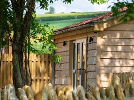 A cabin with a door and window surrounded by trees at The Fox Den in East Coker