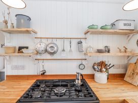 A kitchen with a gas stove and shelves holding various cooking utensils at 4 bed in Anglesey