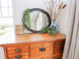 A wooden dresser with a mirror and decorative items at 4 bed in Anglesey
