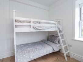 A bunk bed with gray bedding in a bedroom at 4 bed in Anglesey