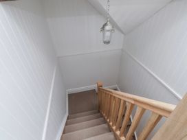 A staircase with wooden banister and light fixture at 4 bed in Anglesey