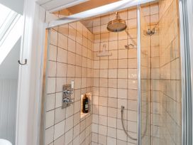 A shower with tiled walls and controls at 4 bed in Anglesey