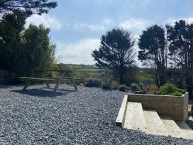 A garden with picnic table and gravel at Arfryn