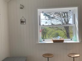 A kitchen with a window and stools at Arfryn in Bull Bay