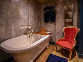 A bathroom with a bathtub and a red chair at The Hollow in Holywell
