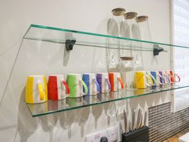 A shelf with colorful mugs and glasses in a kitchen at Rocklands in Shap