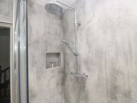 A shower with a chrome shower head and niche with bottles at Rocklands in Shap