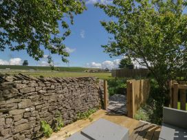 A garden with a stone wall and wooden fence at Rocklands in Shap