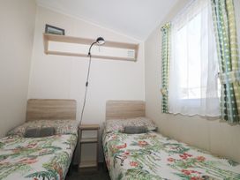 A bedroom with two beds and a shelf at Tower View Number 34 in Pevensey