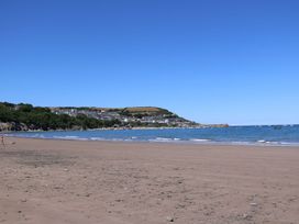 A beach with houses and hills in the background at Hafan Y Gof in Newcastle Emlyn
